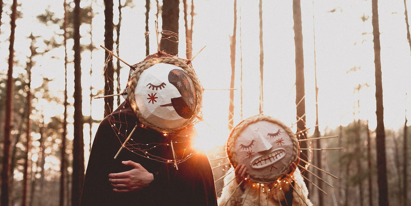 Mākslinieces Diānas Renžinas veidotās meteņu maskas - Saules un Mēness - uz priežu meža fona.