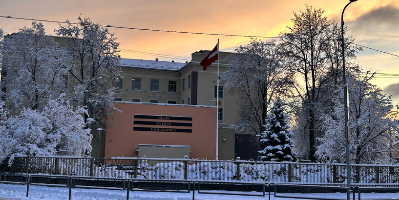 Rīgas Teikas vidusskolas ēka ziemā uz saulrieta fona