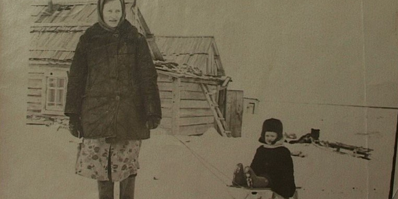 19. gadsimta 50. gadi Sibīrijā, pie koka būdiņas redzama sieviete, kas velk bērnu ragaviņās 
