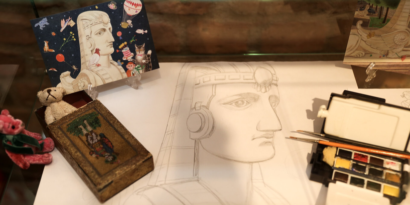 Ilustrācija radošai darbnīcai “Sfinksas smaida noslēpums”, kuras centrā ir ar zīmuli skicēta sfinksas galva