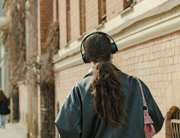 Meitene iet pa ielu un austiņās klausās mūziku