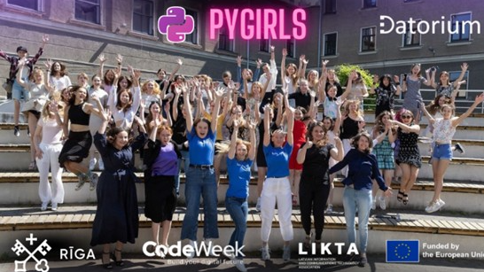 Liela jauniešu grupa pozē uz āra kāpnēm zem uzraksta ‘PYGIRLS’, paceltām rokām atzīmējot programmēšanas apmācību pasākumu.